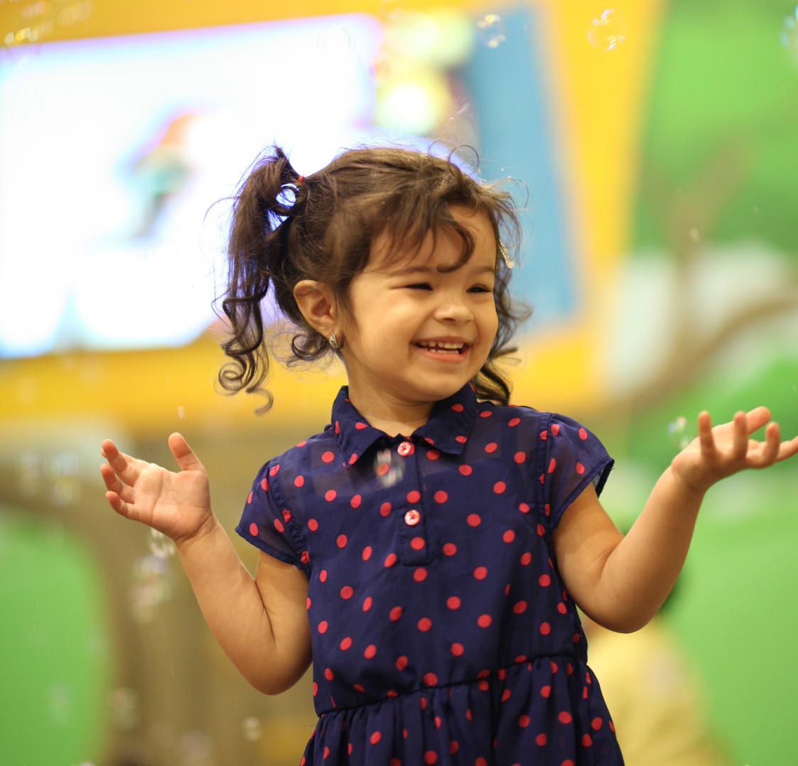 A child smiling and playing with bubbles at Grace Kids